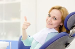 Woman giving a thumbs up in a dental chair