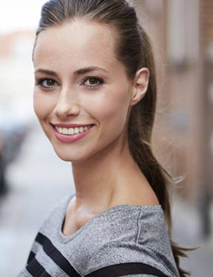 Brunetee woman with smooth skin smiling, for information on dermal fillers from Dr. Cha in Tulsa