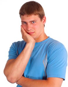man in a blue clothes posing on white holding his jaw in pain