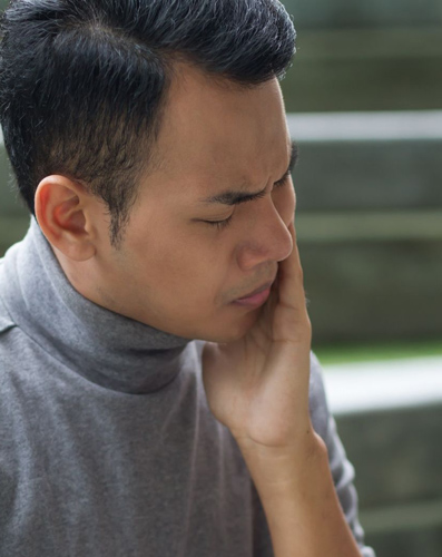 Man holding his face portraying tooth sensitivity to cold