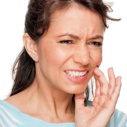 Woman holding the side of her face and portraying pain from a cracked tooth
